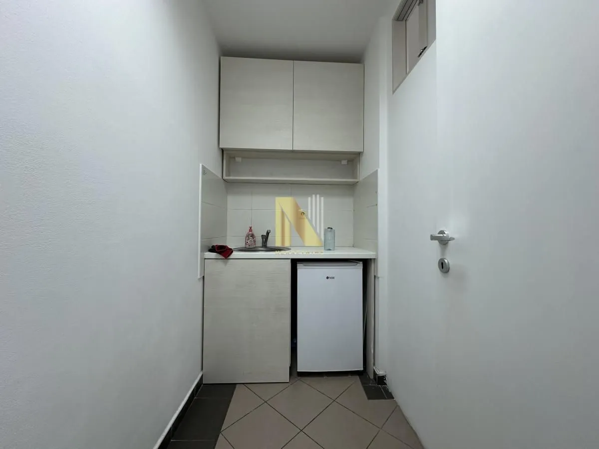 Small kitchen with a sink, cabinetry, and a refrigerator.