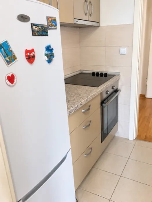 Small kitchen with a white refrigerator, stove, and beige kitchen cabinets.