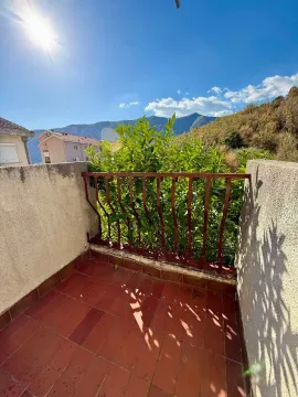 Manji popločani balkon sa metalnom ogradom i pogledom na planine. - image 6
