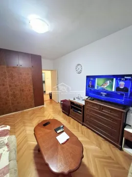 Dnevna soba sa drvenim nameštajem, televizorom i parketom na podu. - image 3