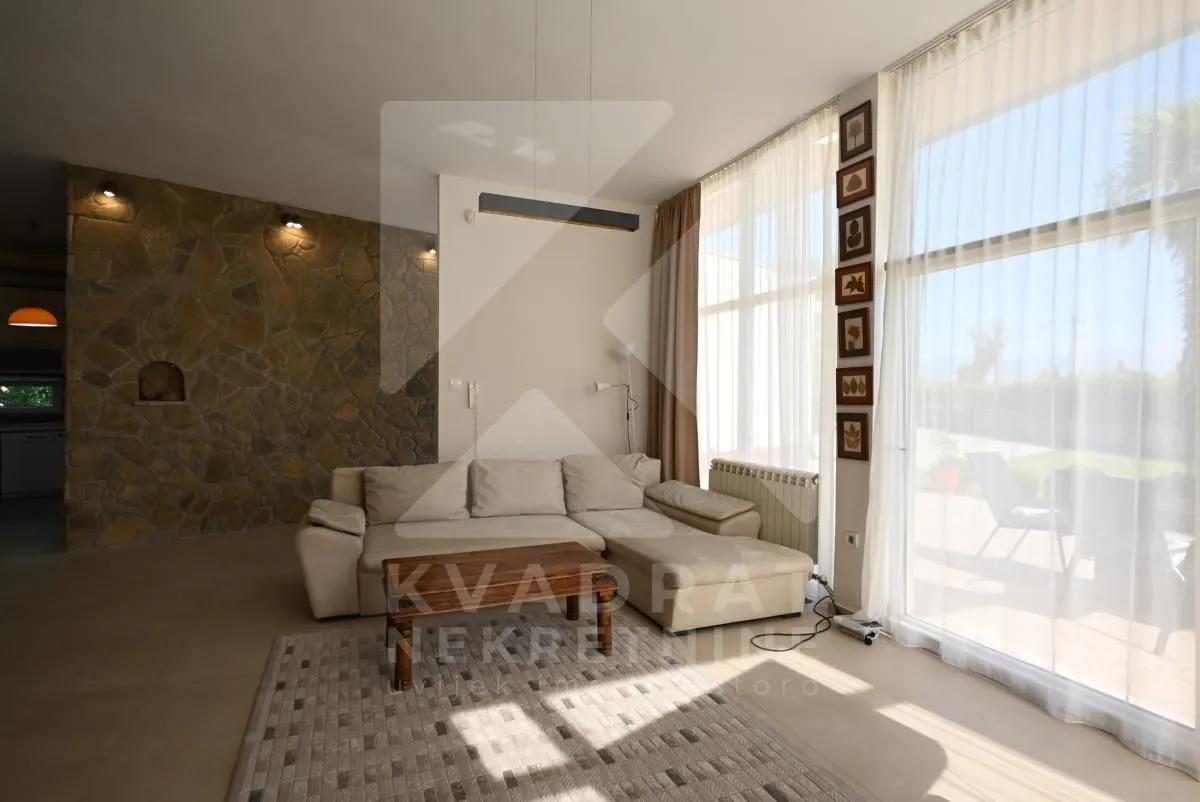 Spacious living room with a sofa and large glass surfaces.