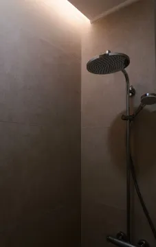 Krupni kadar tuš kabine sa slavinom na popločanom zidu. - image 14