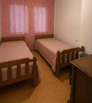 Bedroom with two wooden beds and pink curtains. - image 7