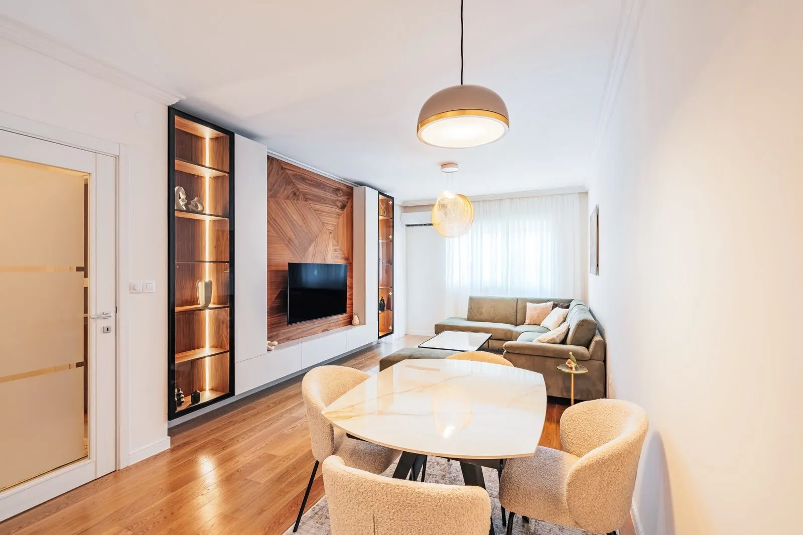 Modern living room with a dining area, sofa, and built-in units.