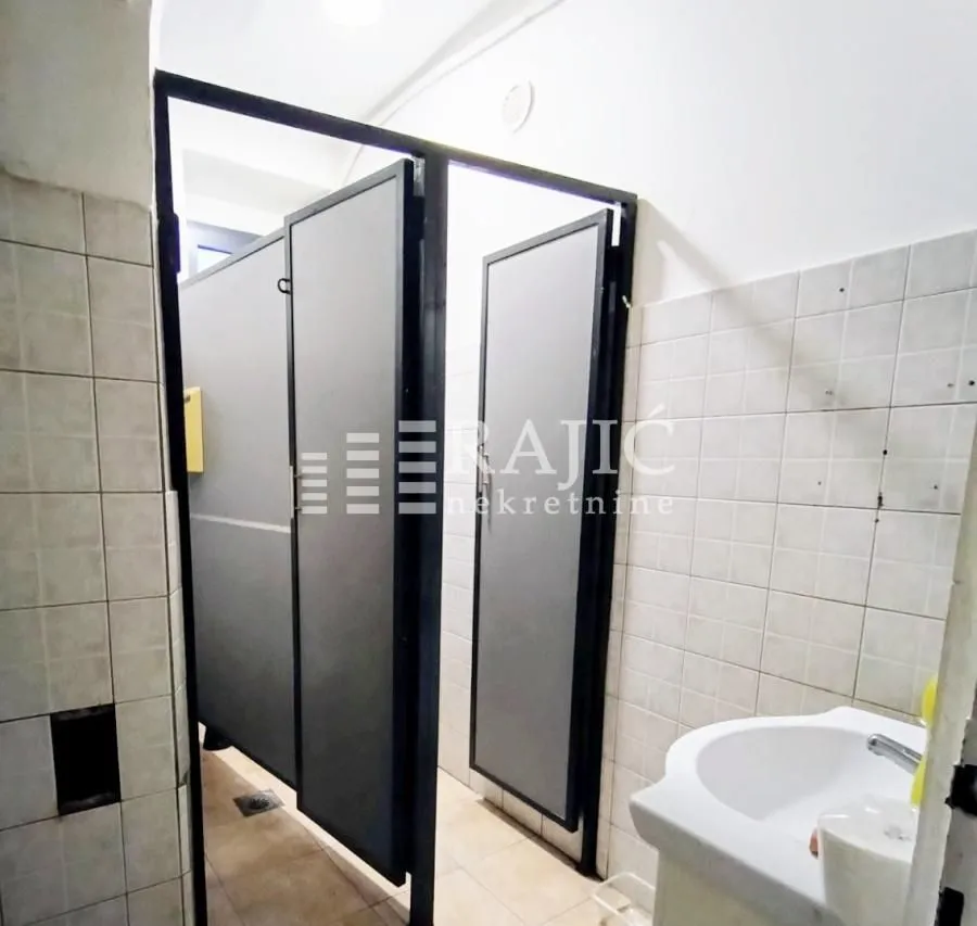 View of a bathroom section with a sink and partition cabins.