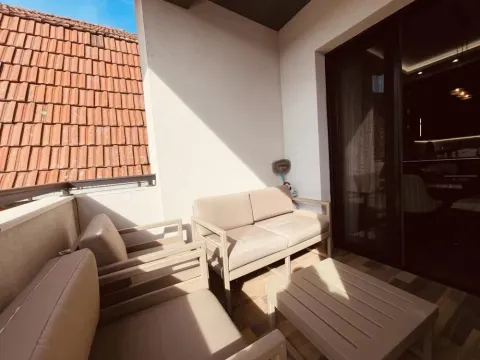 Nameštena terasa sa garniturom za sedenje i pogledom na krovove. - image 16