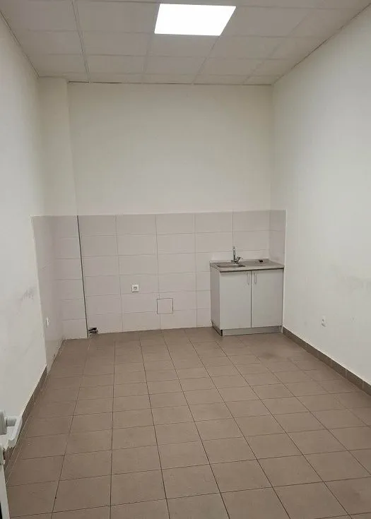 Empty room with ceramic tiled flooring and a small sink unit against the wall.