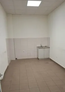 Empty room with ceramic tiled flooring and a small sink unit against the wall. - image 9