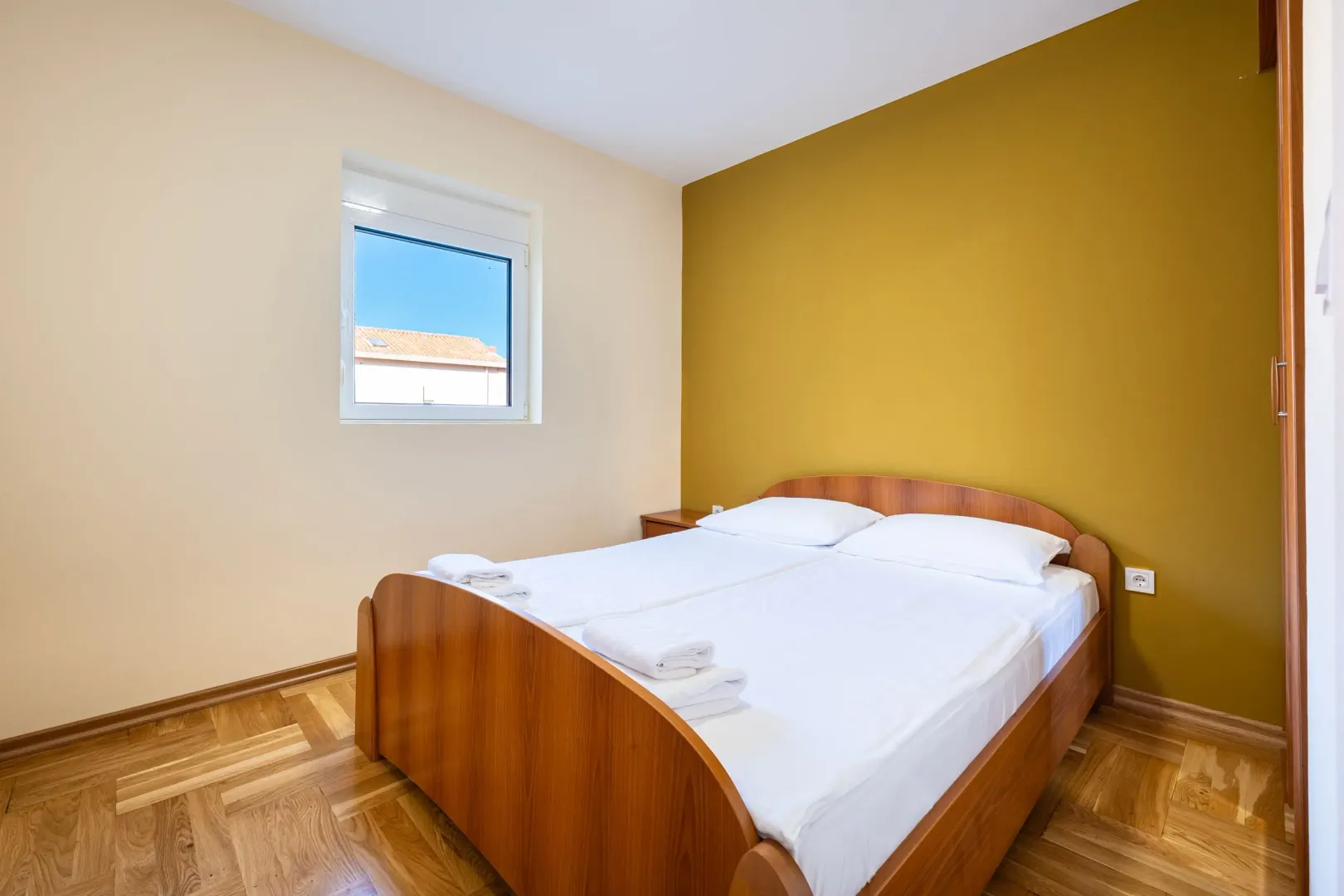 Bedroom with a double bed, wooden floor and a window.