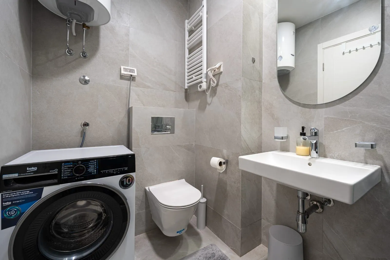 Modernly equipped bathroom with a washing machine, washbasin, and shower area.