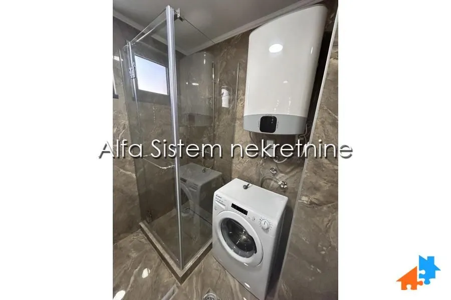 Bathroom with a shower cabin, water heater, and washing machine.