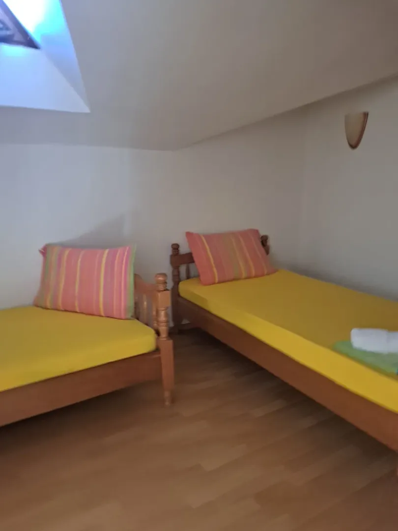Potkrovlje opremljeno sa dva drvena kreveta sa žutim posteljina.
