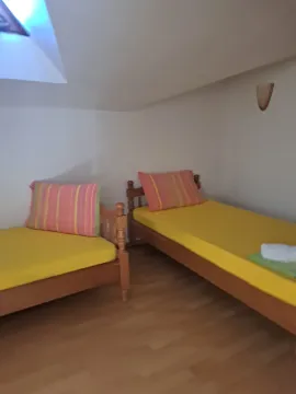 Potkrovlje opremljeno sa dva drvena kreveta sa žutim posteljina. - image 5