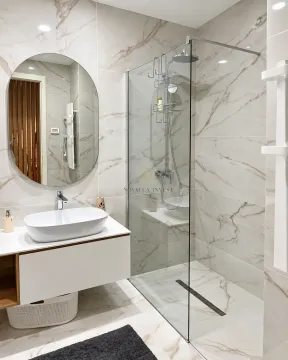Modern bathroom with a walk-in shower, washbasin, and round mirror. - image 10