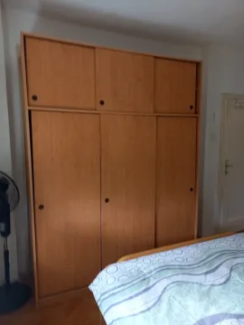 A bedroom featuring a large wooden wardrobe and a bed. - image 9