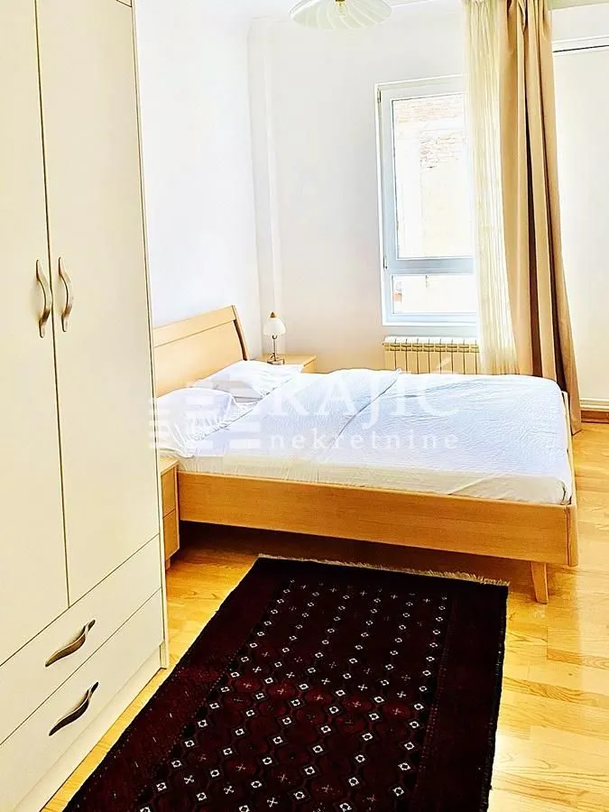 Bright bedroom with a double bed, wardrobe, and a window.