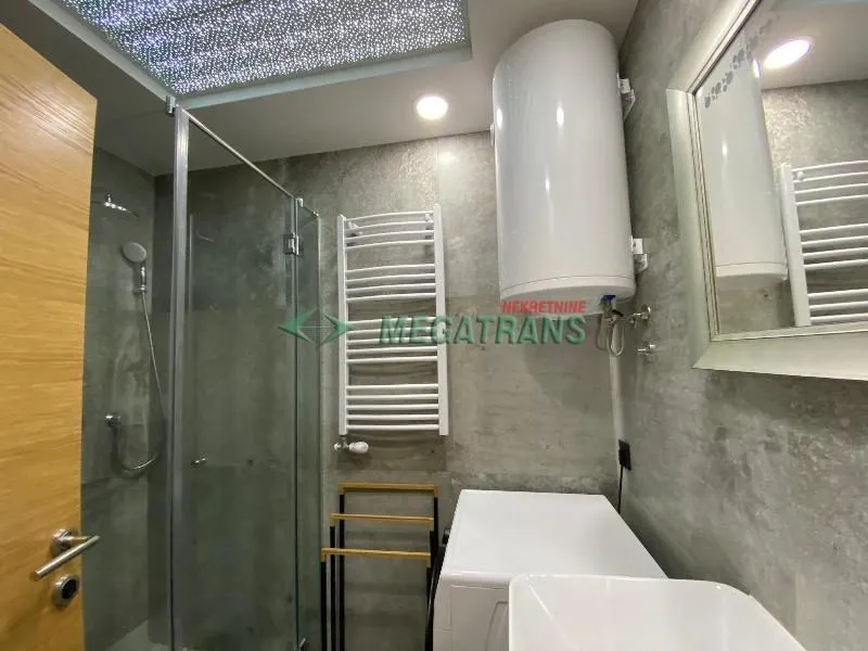 Modernly equipped bathroom with a walk-in shower, water heater, and washbasin.