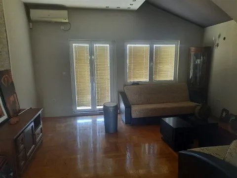 Living room with wooden floors, a sofa, and windows with blinds. - image 6