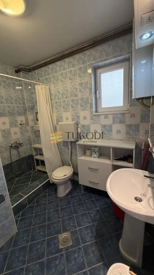 Tiled bathroom with a shower cabin, washbasin, and toilet.