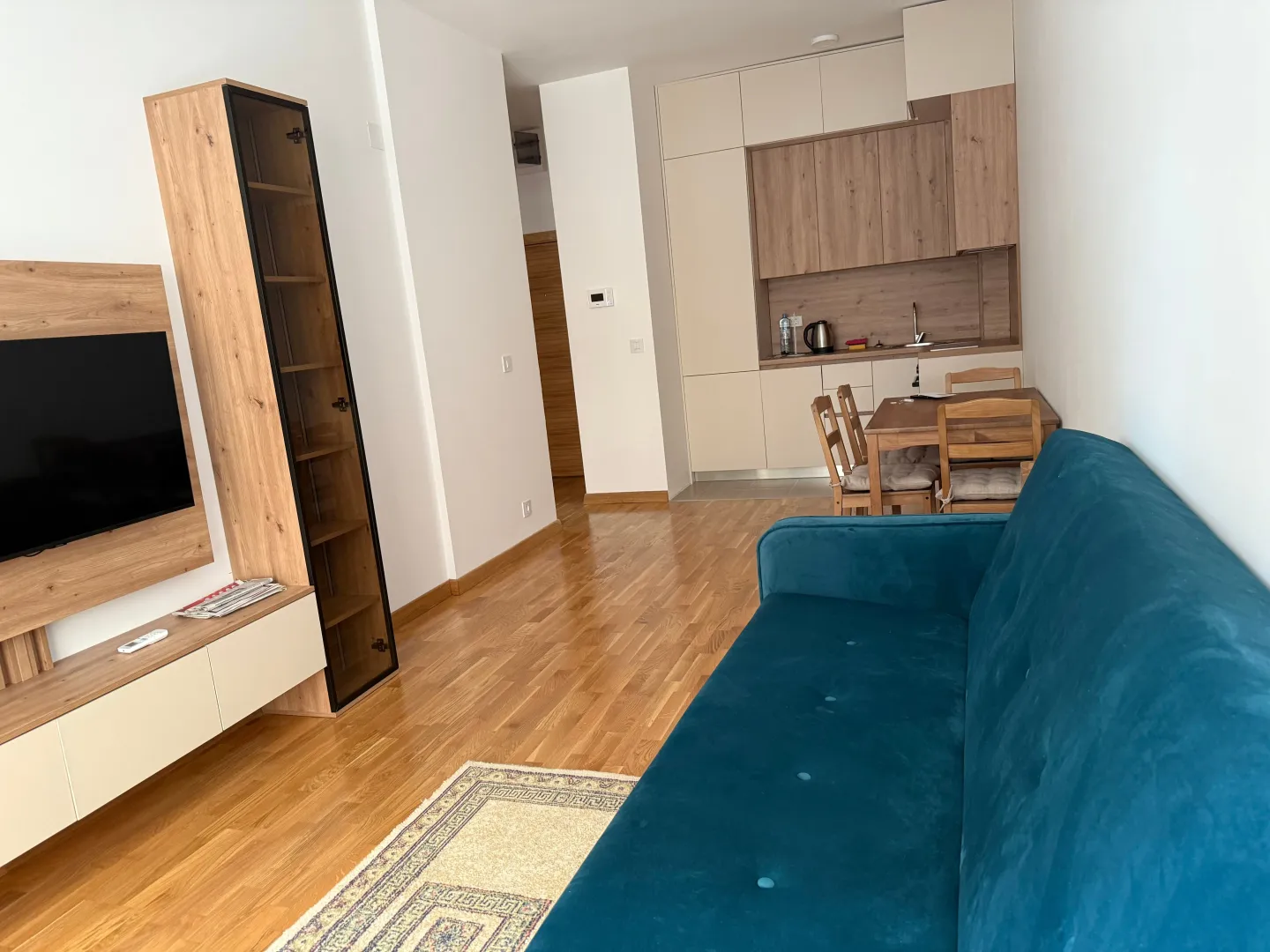 Living room with a sofa, TV unit, and dining area integrated with the kitchen.