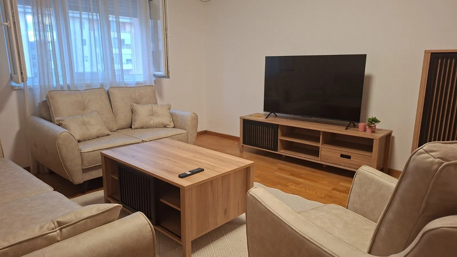 Dnevna soba sa garniturom, stočićem i televizorom.