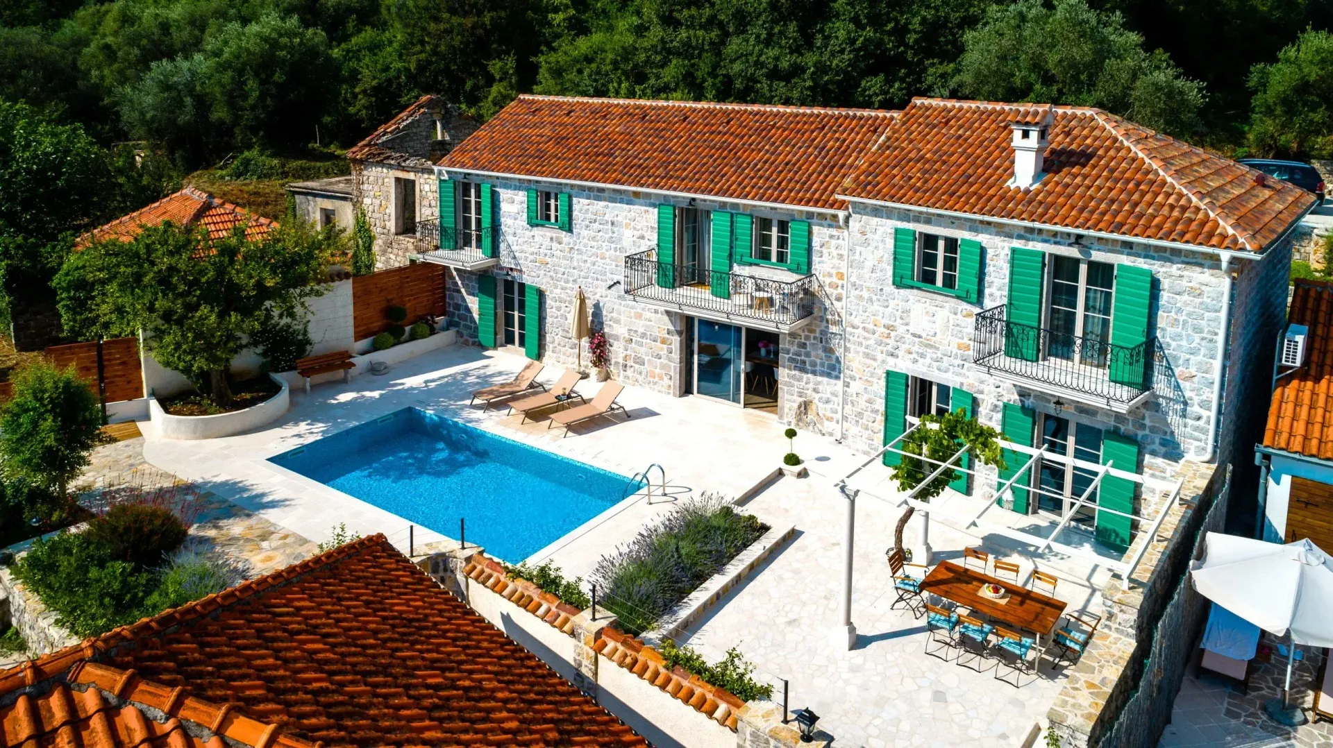 Aerial view of a stone house with a swimming pool and landscaped courtyard.