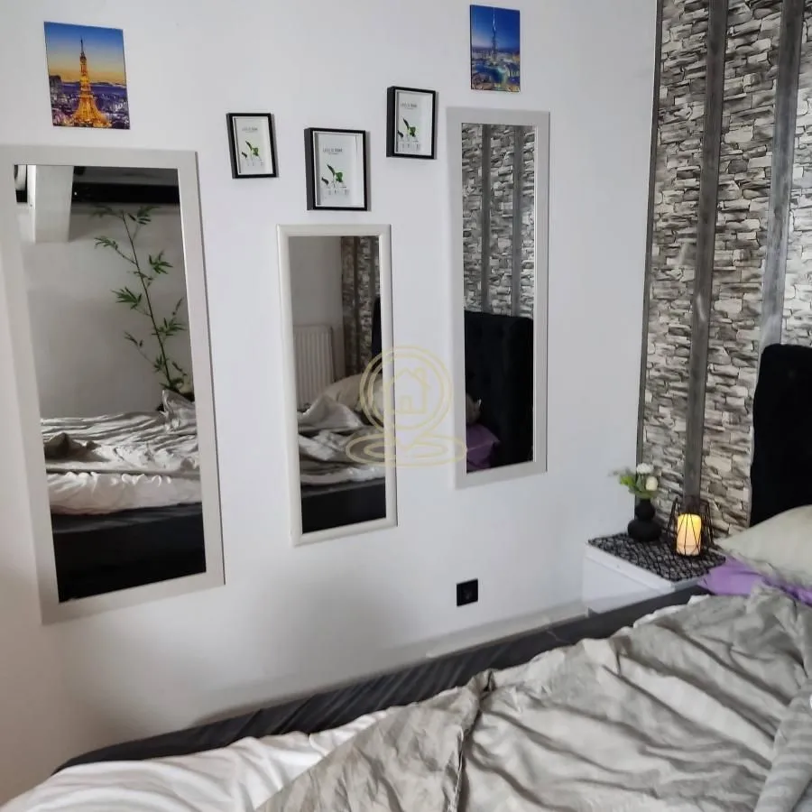 Spavaća soba sa bračnim krevetom i ogledalima na zidu.