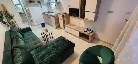 Dnevna soba sa garniturom, televizorom i kuhinjom u pozadini. - image 13