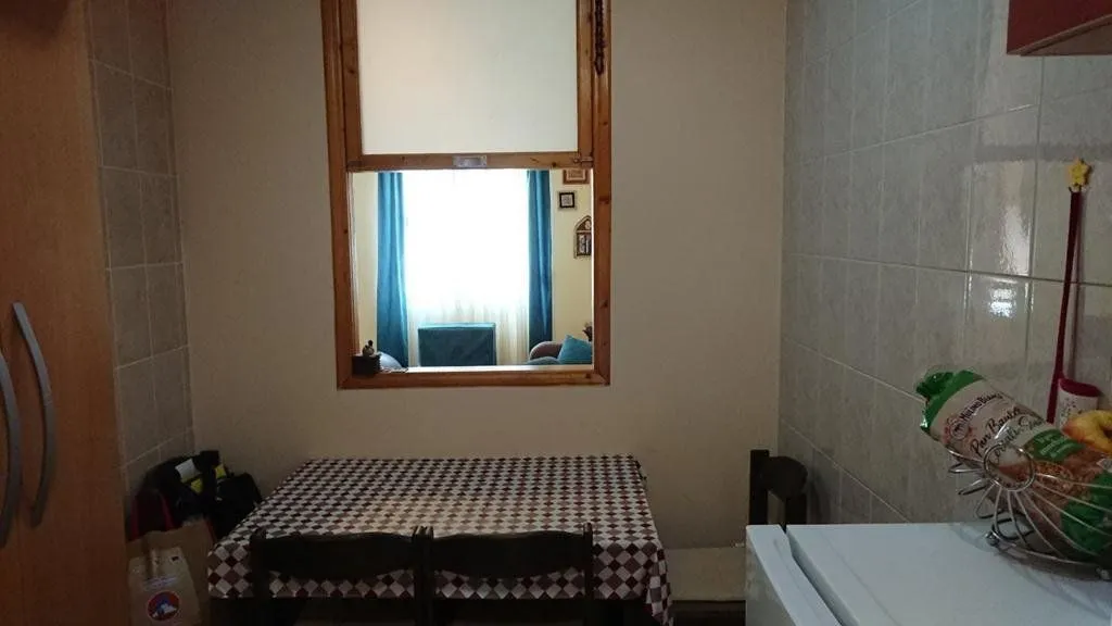 Small dining area with a table, chairs, and a window looking into another room.