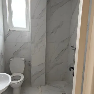 Smaller bathroom tiled with marble tiles, featuring a toilet, sink, and shower. - image 14