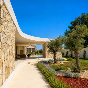 Exterior of the house with a paved pathway, landscaped yard, and olive trees. - image 2