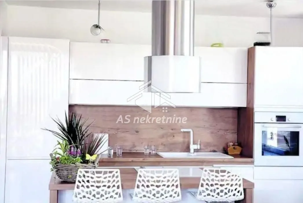 Modern white kitchen with wooden details and a breakfast bar.