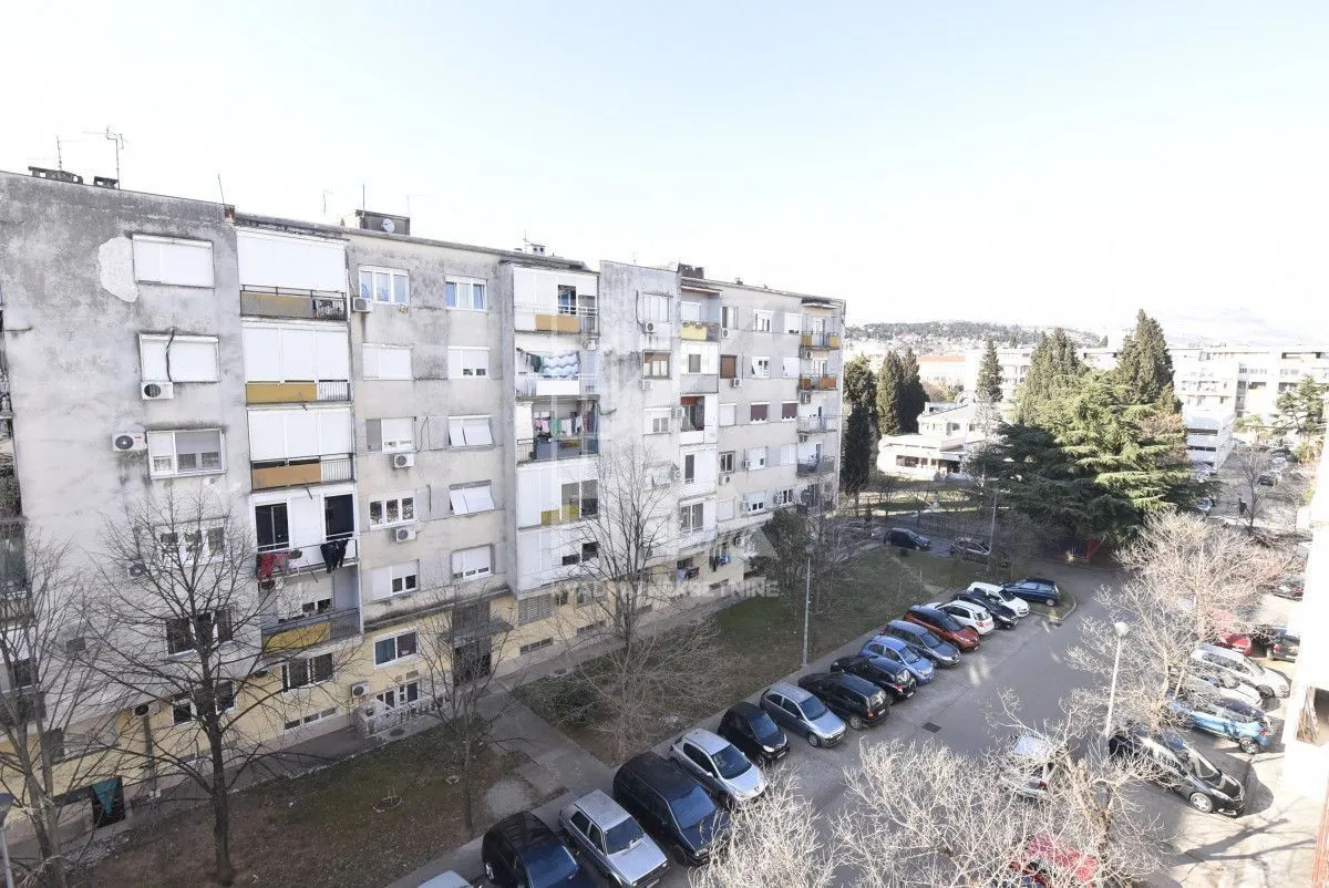 View of a multi-story residential building and the parking lot in front.