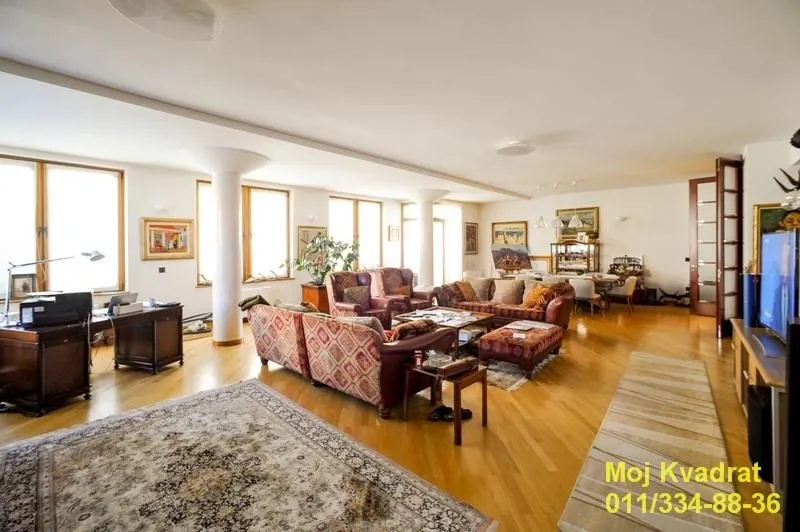 Spacious living room with a seating set, a desk, and a dining area in the background.