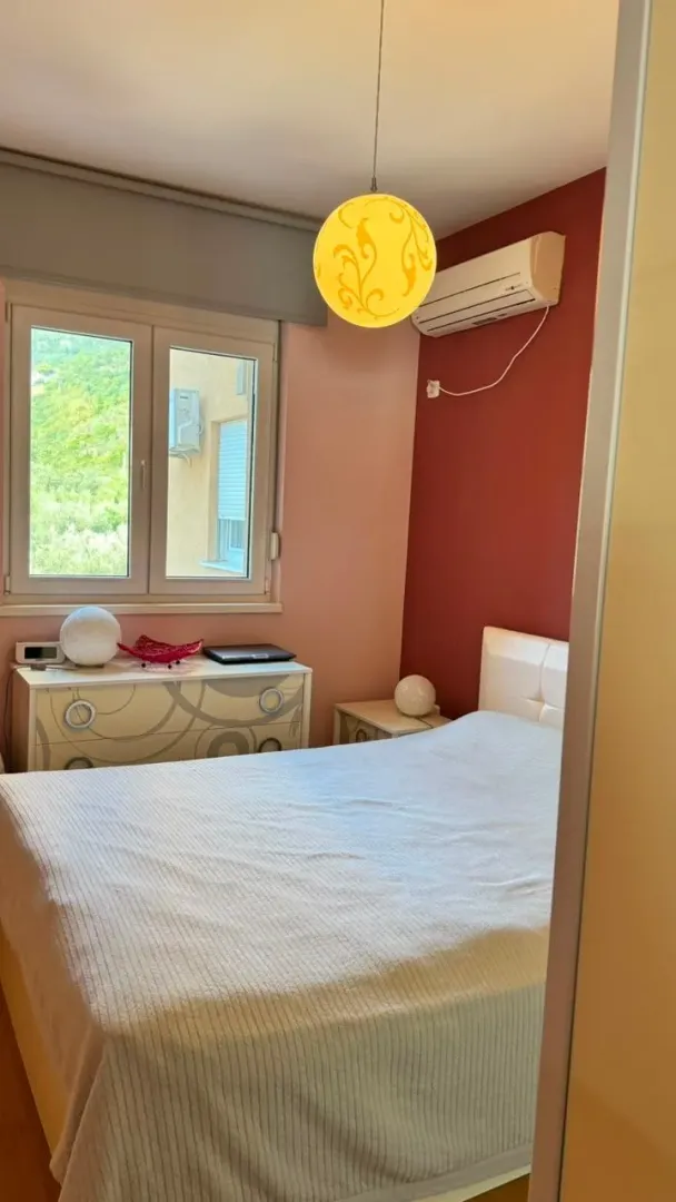 Namještena spavaća soba sa bračnim krevetom, klima uređajem i prozorom.