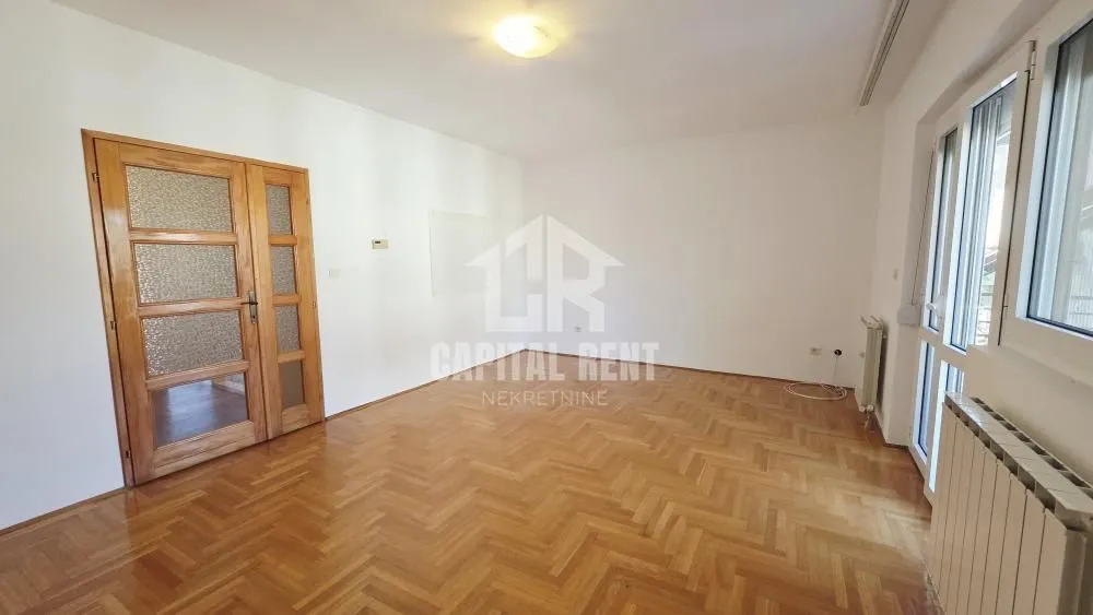 Empty room with hardwood parquet flooring, white walls, and wooden doors.