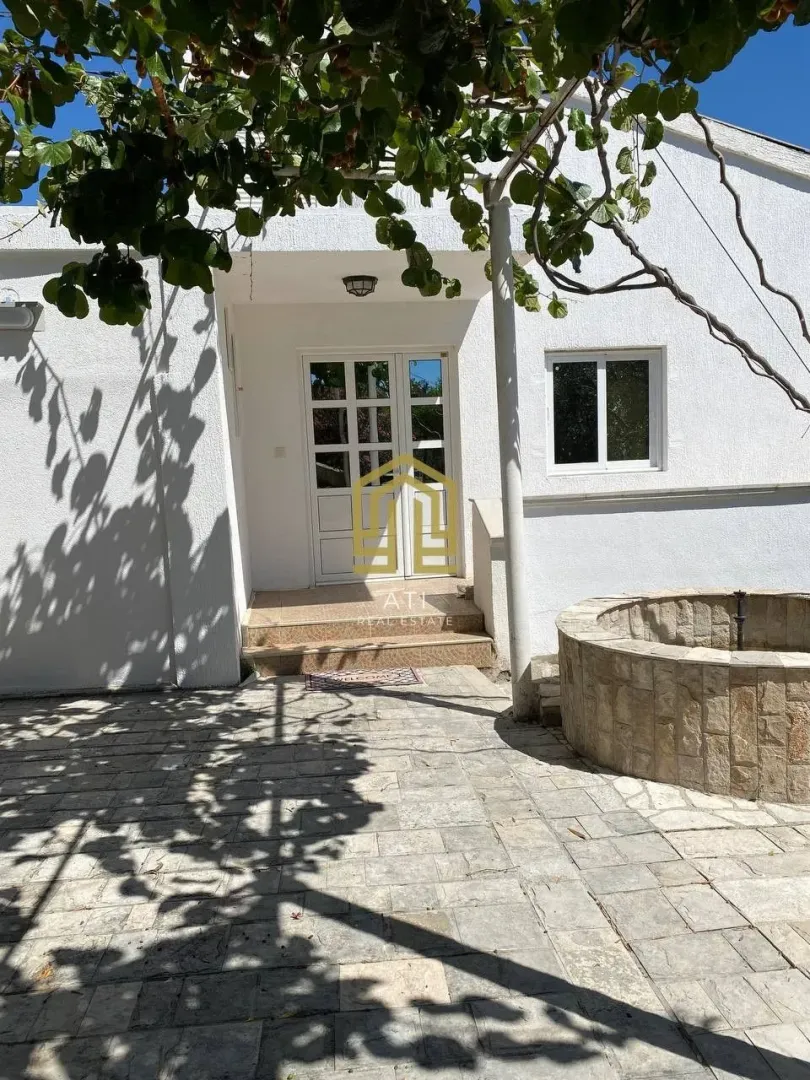 Dvorište kuće sa popločanim platoom i ulaznim vratima.