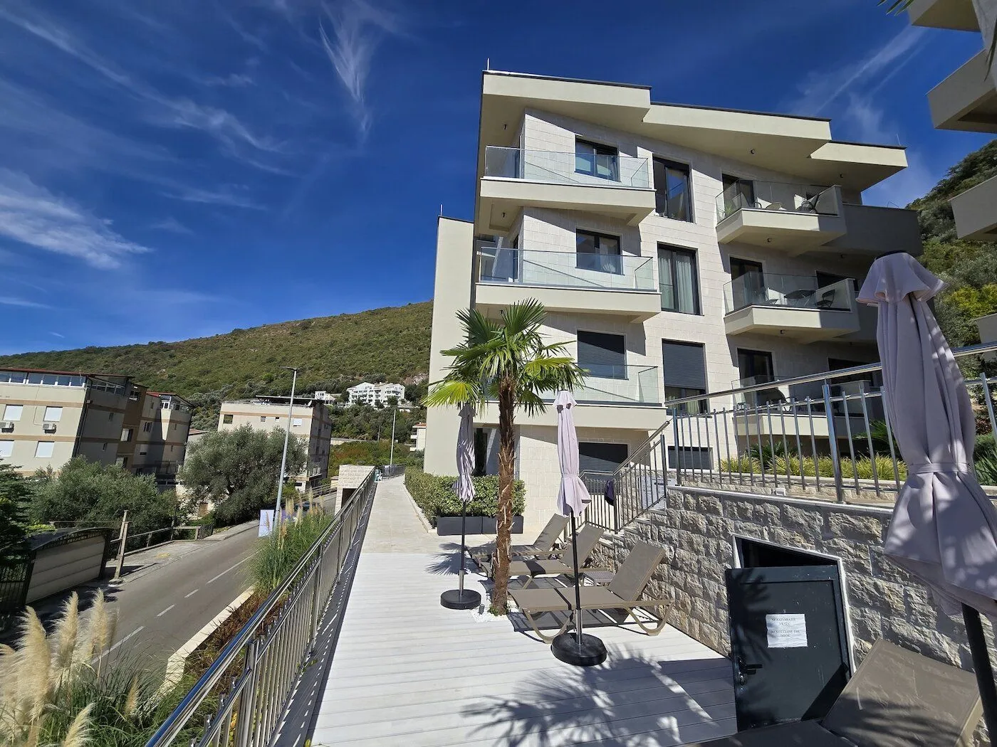 Exterior of a modern residential building with a furnished terrace and sun loungers.