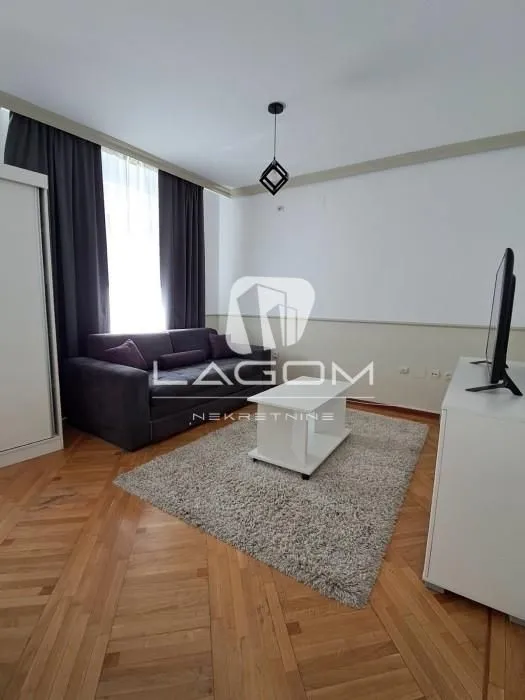 Dnevna soba sa garniturom, stočićem i televizorom.