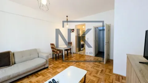 Living room with a sofa, dining table, and a view of the kitchen. - image 2