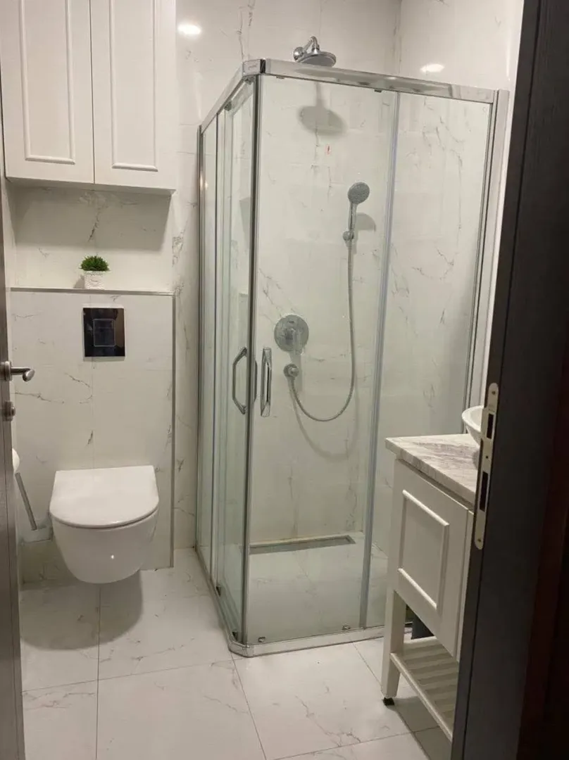 Moderne kupatilo sa tuš kabinom, umivaonikom i ugradnom wc šoljom.