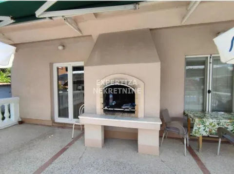 Covered terrace with a built-in barbecue and seating set. - image 4