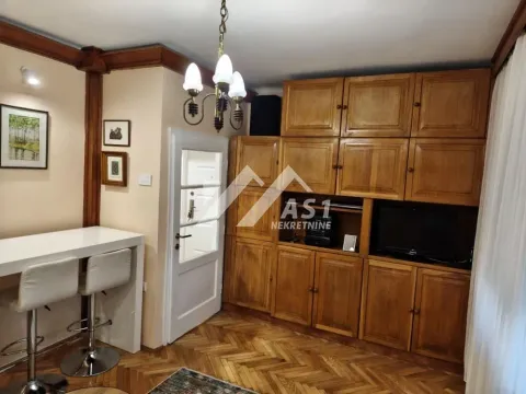 Dnevna soba sa velikim drvenim ormarom, šankom sa barskim stolicama i TV-om. - image 3