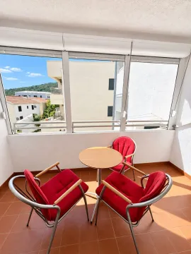 Enclosed balcony with seating furniture and a view of the surroundings. - image 12