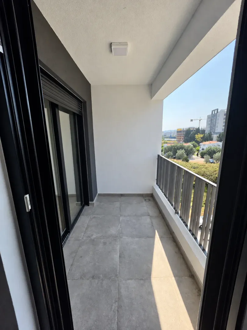 Manji natkriveni balkon sa sivim keramičkim pločicama i pogledom na okolinu.