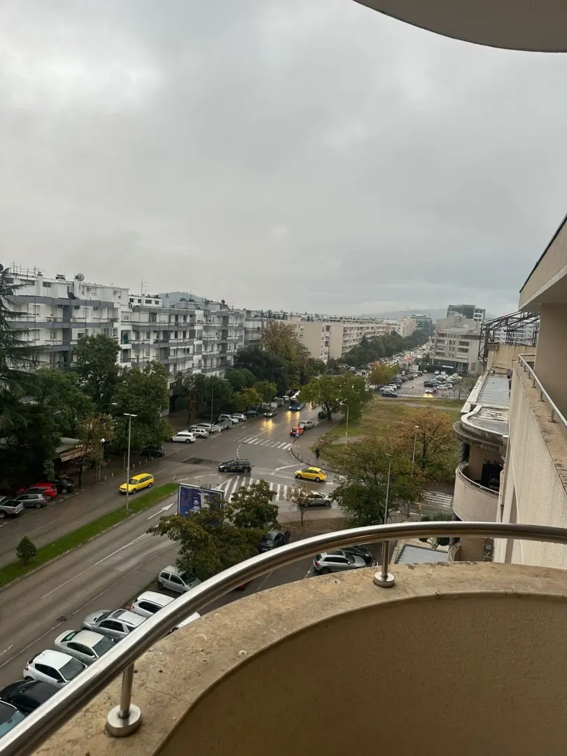 Pogled sa balkona na gradsku ulicu i zgrade tokom oblačnog dana.