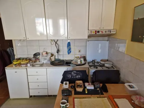 Older kitchen with white cabinetry and a dining table in the foreground. - image 2