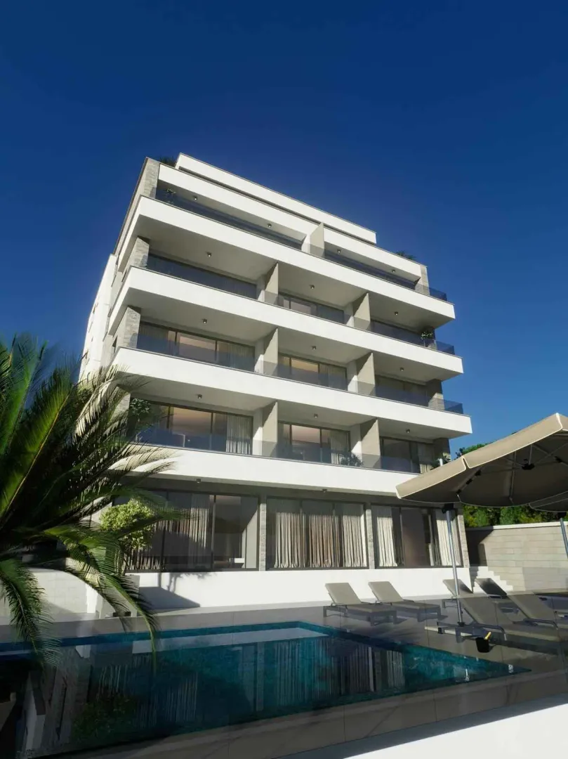 Spoljašnji izgled moderne stambene zgrade sa bazenom i ležaljkama.