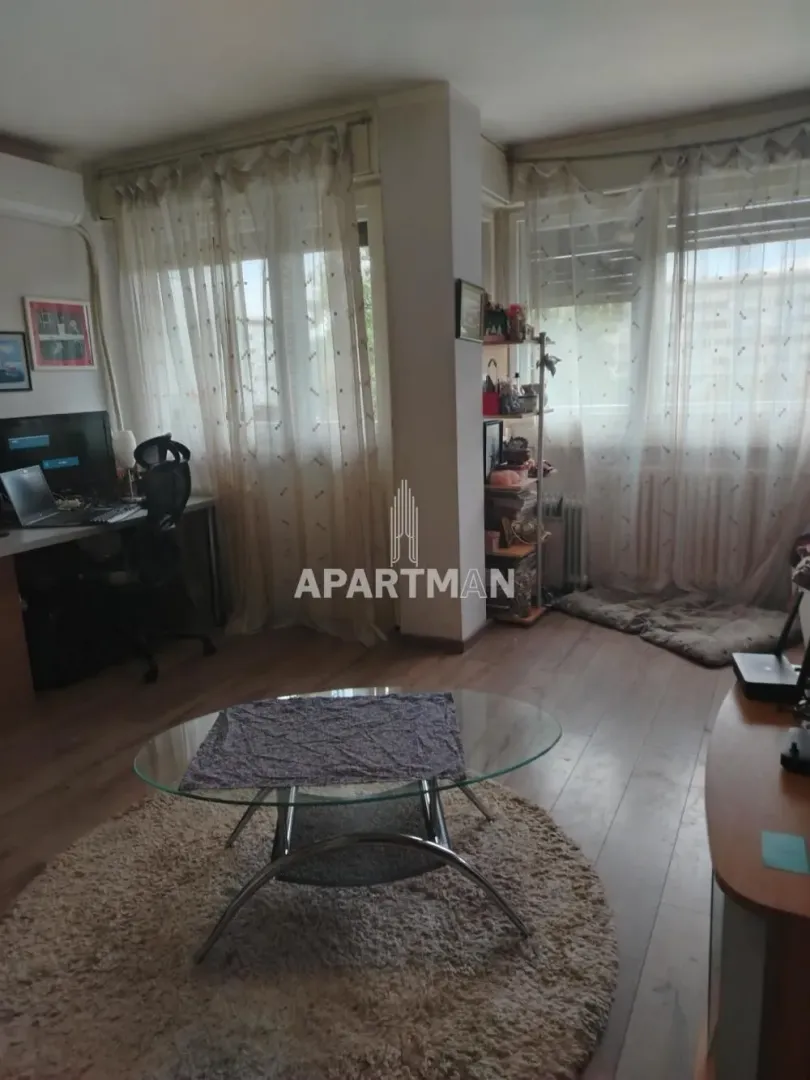 Dnevna soba sa radnim stolom i staklenim stočićem pored prozora.