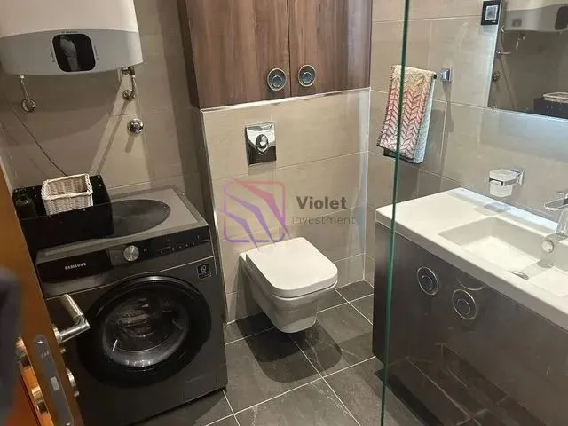 Moderne kupatilo sa tuš kabinom, umivaonikom, WC šoljom i veš mašinom.